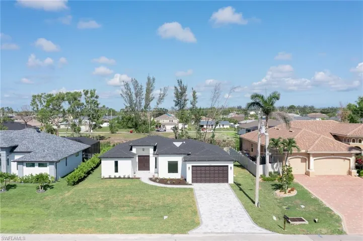 View of front of home with a residential view, decorative driveway, and a garage
