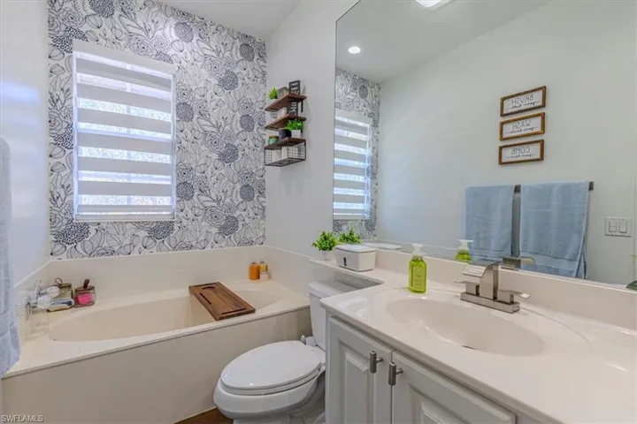 Full bathroom featuring vanity, a garden tub, wallpapered walls, and recessed lighting