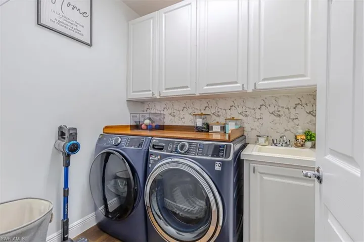 Laundry room with separate washer and dryer, cabinet space, and wood finished floors