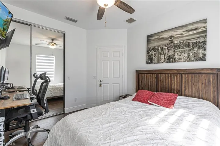 Bedroom with a desk, wood finished floors, a closet, and a ceiling fan