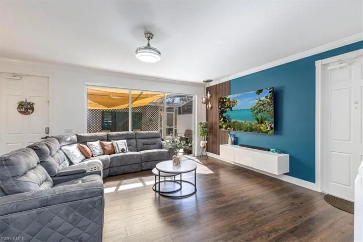 Living room featuring crown molding, wood-type flooring, and a textured ceiling