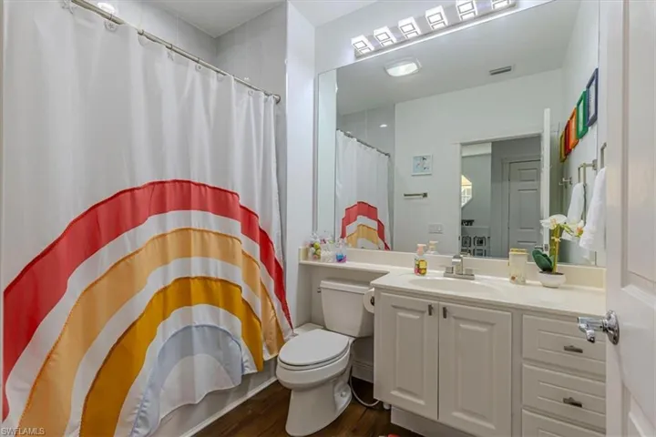 Full bath with curtained shower, vanity, and dark wood-style flooring