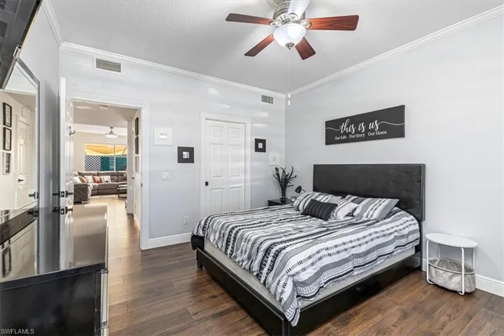 Bedroom with crown molding, dark wood-style floors, a textured ceiling, and ceiling fan