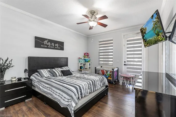 Bedroom featuring ornamental molding, dark wood-style floors, a textured ceiling, and ceiling fan