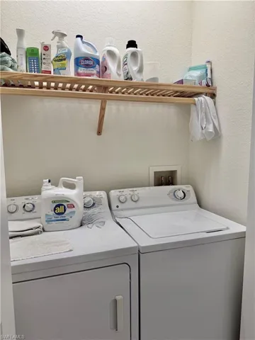 Washroom with a textured wall and washer and clothes dryer