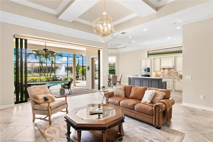 Living room featuring ceiling fan, a sunroom, hanging lights, and ornamental molding