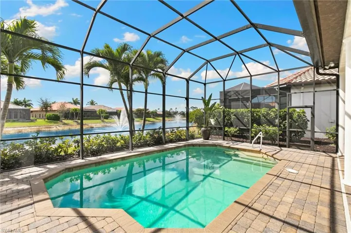 Outdoor pool featuring a sunroom, glass enclosure, a water view, and a patio