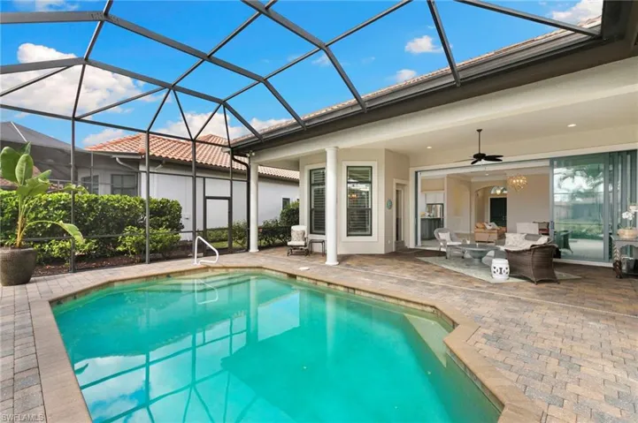 Outdoor pool featuring glass enclosure, a sunroom, a patio, and an outdoor living space