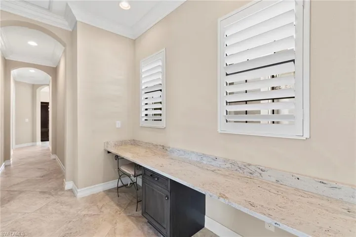 Hall with an office area, arched walkways, crown molding, and recessed lighting