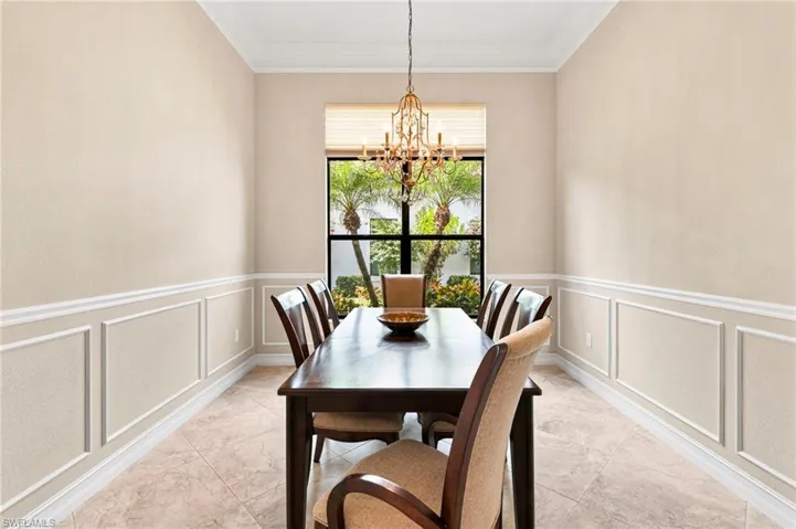 Dining area featuring crown molding, a decorative wall, and hanging lights