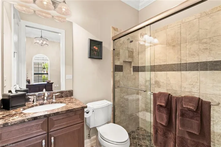 Full bath with ornamental molding, vanity, a shower stall, and hanging lights