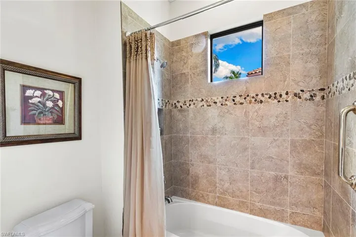 Bathroom featuring shower / bath combination with curtain and toilet