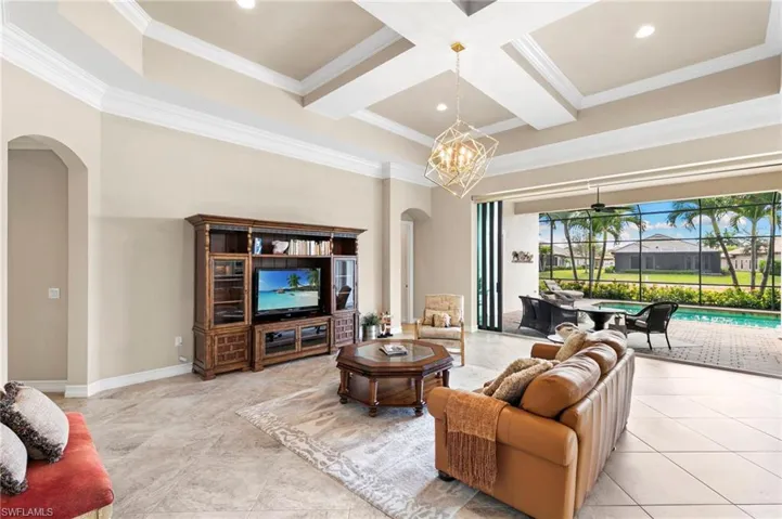 Living area with arched walkways, coffered ceiling, ornamental molding, recessed lighting, and ceiling fan