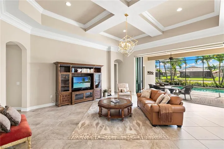 Living room featuring arched walkways, coffered ceiling, ornamental molding, recessed lighting, and ceiling fan
