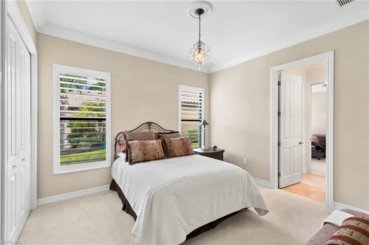 Bedroom with light colored carpet, a closet, crown molding, and suspended lighting