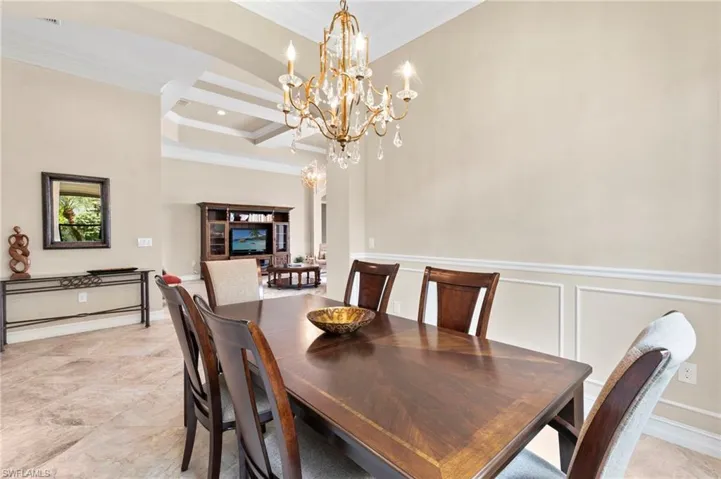 Dining room with ornamental molding, a decorative wall, and hanging lights