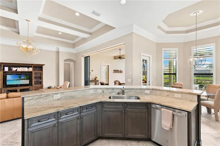 Kitchen featuring hanging lights, open floor plan, dishwasher, and crown molding
