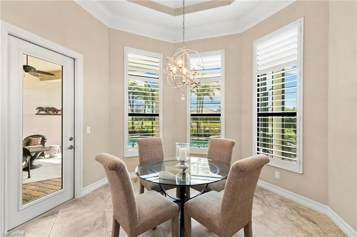 Dining area featuring ornamental molding, a chandelier, a tray ceiling, and light tile patterned floors
