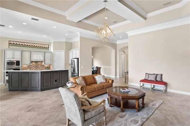 Living area featuring suspended lighting, arched walkways, and ornamental molding