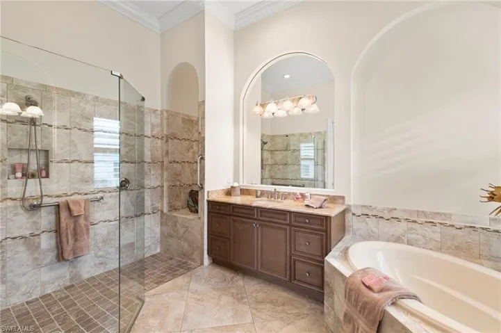 Full bathroom featuring a garden tub, vanity, a shower stall, and crown molding