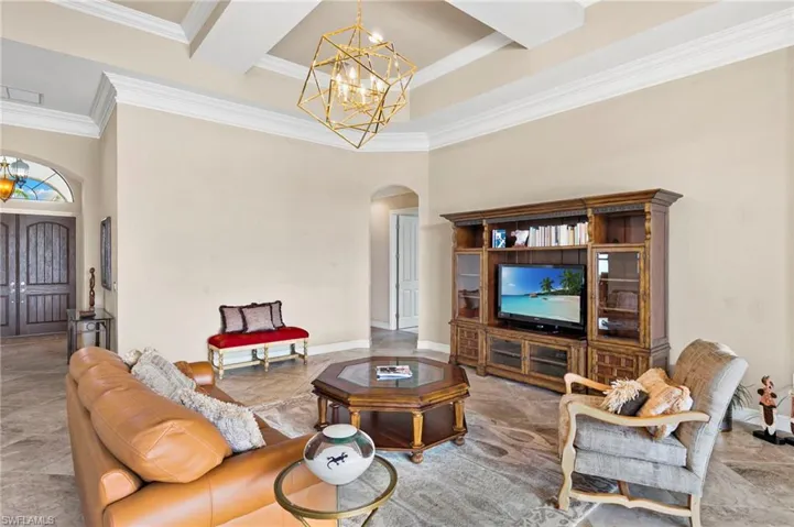 Living area with a chandelier, arched walkways, a high ceiling, and ornamental molding