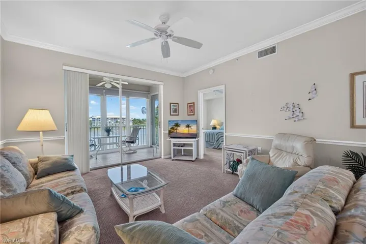 Living area featuring light neutral walls, crown molding, and carpeting