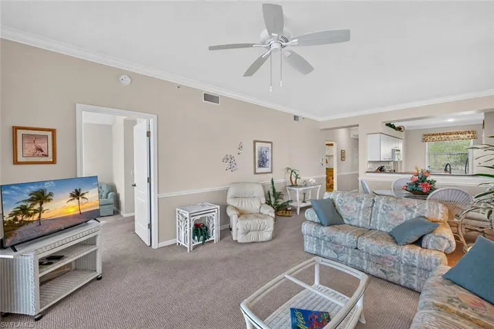 Living room featuring neutral-toned walls, crown molding, and carpeted flooring