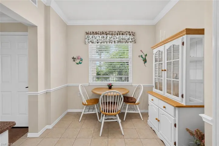 Recessed dining area featuring tile flooring, a window with horizontal blinds, and crown molding