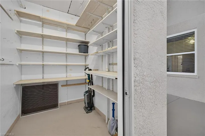 Utility closet featuring extensive built-in adjustable shelving, light beige flooring, and white wall finishes