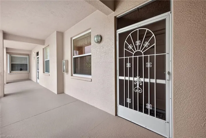 Entryway featuring a decorative security door, textured stucco exterior, and dual-pane windows