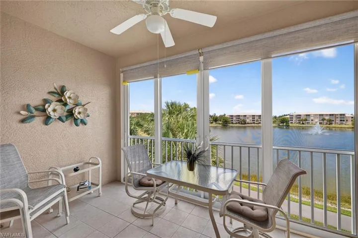 Screened balcony featuring expansive water views, a ceiling fan, and tiled flooring