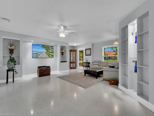 Living room with built in features, ceiling fan, and a textured ceiling