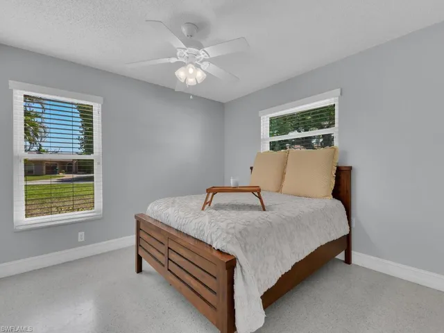 Bedroom featuring a textured ceiling, multiple windows, and ceiling fan