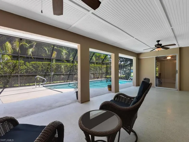 View of swimming pool featuring a patio, glass enclosure, and ceiling fan