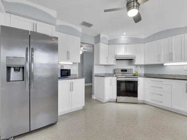 Kitchen featuring ceiling fan, white cabinets, and appliances with stainless steel finishes