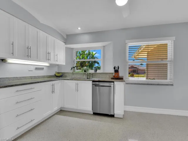 Kitchen featuring dark stone countertops, sink, white cabinetry, and stainless steel dishwasher