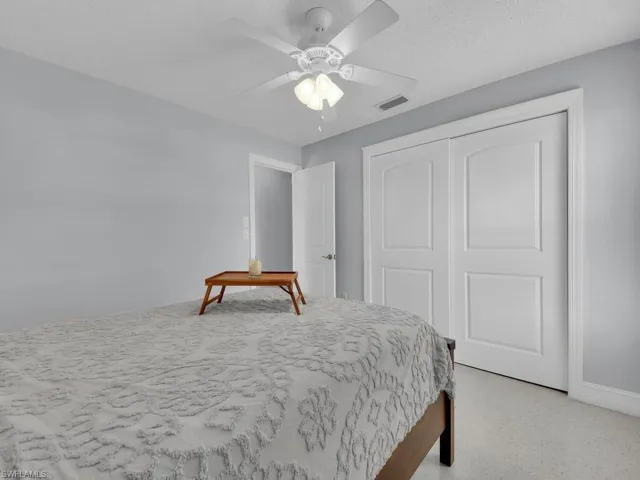 Bedroom featuring a textured ceiling, a closet, ceiling fan, and light colored carpet
