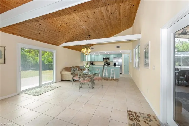 Dining area featuring light tile patterned floors, wood ceiling, healthy amount of natural light, high vaulted ceiling, and baseboards