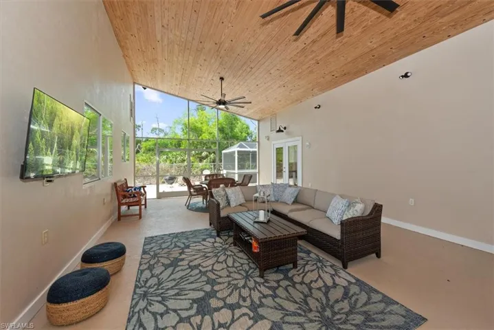 Living room with a ceiling fan, high vaulted ceiling, wood ceiling, plenty of natural light, and a sunroom