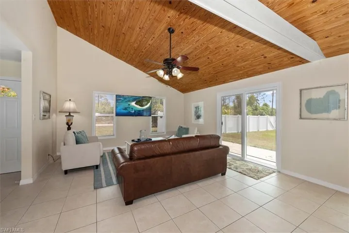 Living area with wood ceiling, light tile patterned floors, baseboards, a ceiling fan, and high vaulted ceiling