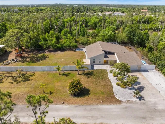 Aerial view of property and surrounding area with a forest
