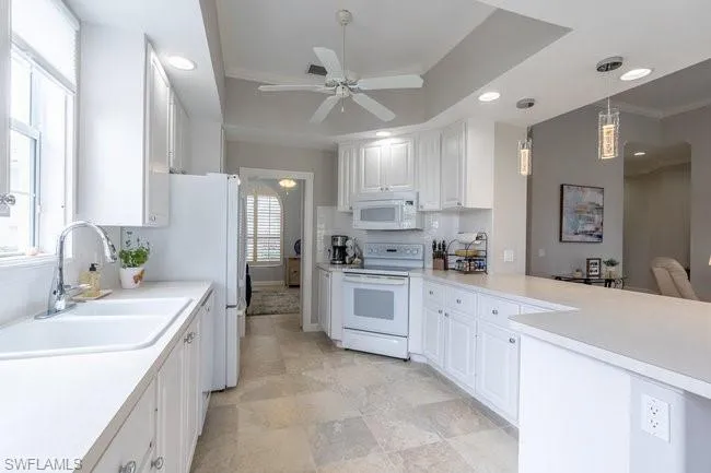 Kitchen with a wealth of natural light, white cabinets, and white appliances