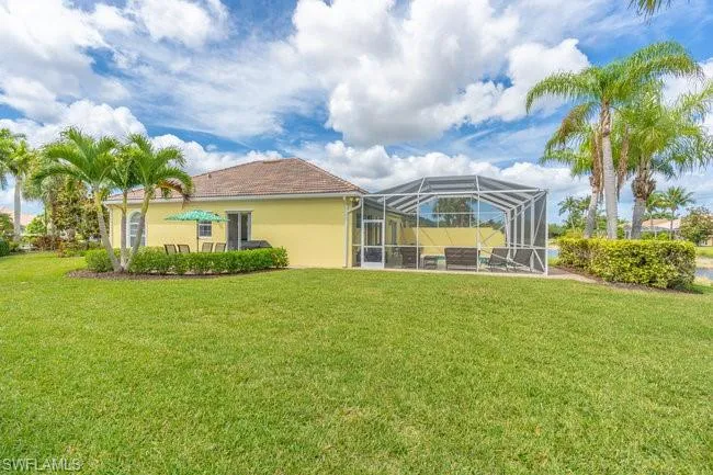 Rear view of property featuring a yard and glass enclosure