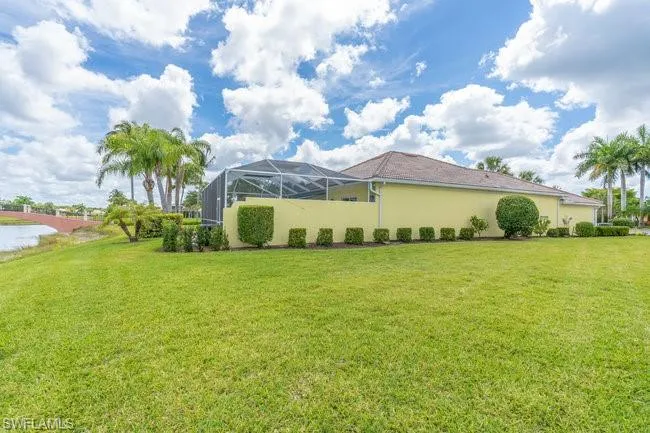 View of property exterior featuring a lawn and glass enclosure