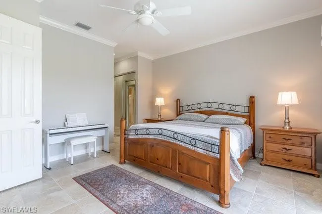 Tiled bedroom featuring ceiling fan, ornamental molding, and a closet