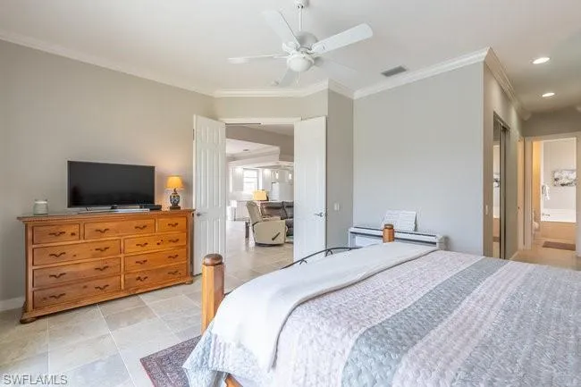 Tiled bedroom with ceiling fan, ensuite bathroom, and crown molding