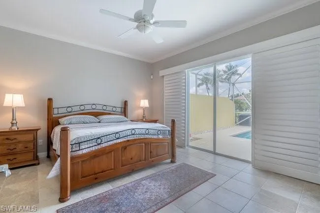 Tiled bedroom featuring ceiling fan, ornamental molding, and access to outside