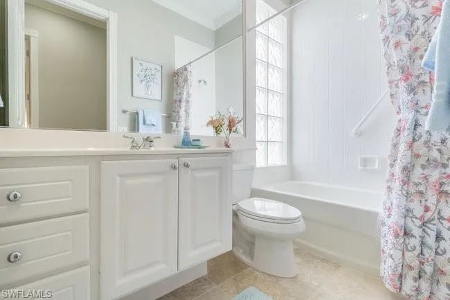 Full bathroom with vanity, tile patterned floors, crown molding, toilet, and shower / bathtub combination with curtain