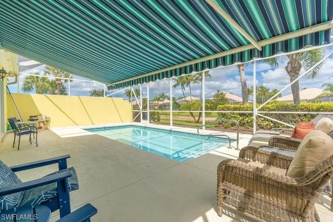 View of swimming pool featuring an outdoor living space, glass enclosure, and a patio area