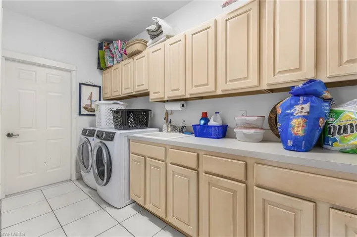 Laundry room with cabinet space, washing machine and clothes dryer, and light tile patterned floors